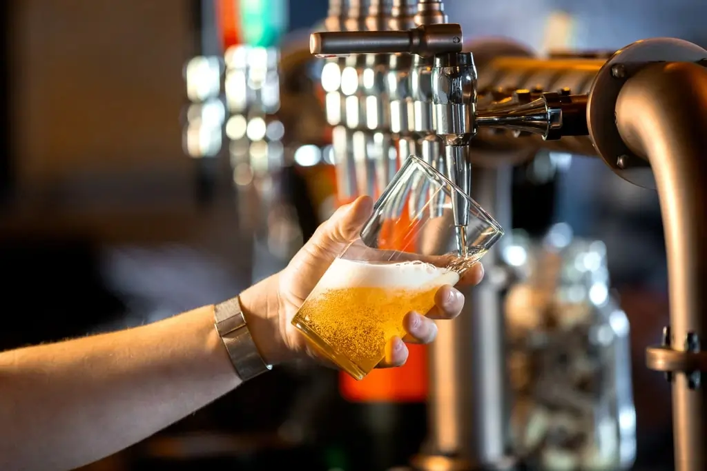 Fresh beer being poured from a tap into an angled glass at Agio Bar, highlighting the craft beer menu