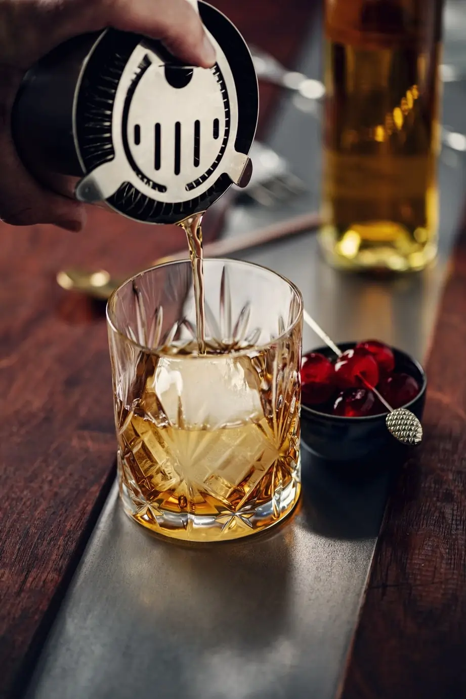 Whiskey cocktail with a large ice cube being prepared at Agio Bar, representing the classic cocktails menu